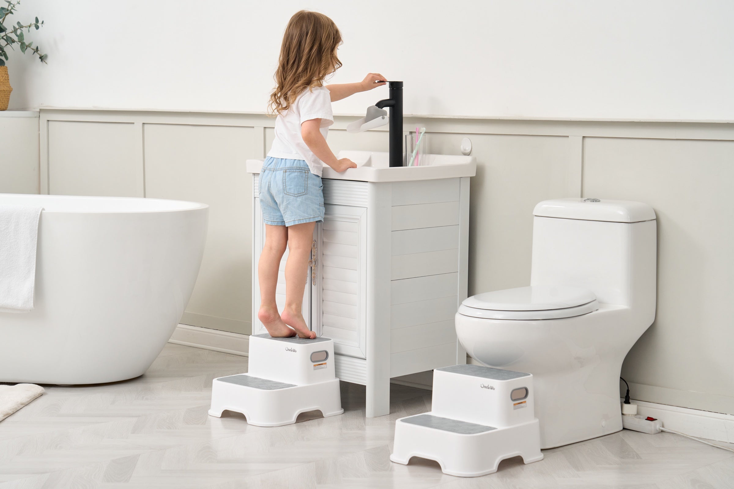 Child using an UncleWu step stool at the bathroom sink